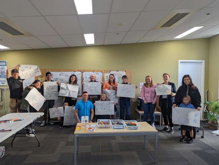 Participants lining up against the wall showing final sketches after an icon jam exercise