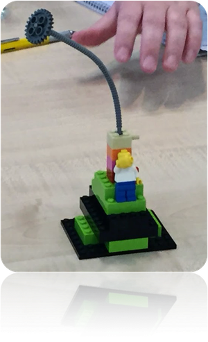 Lego model of a project with a bendy stick on top and a person standing by a tower